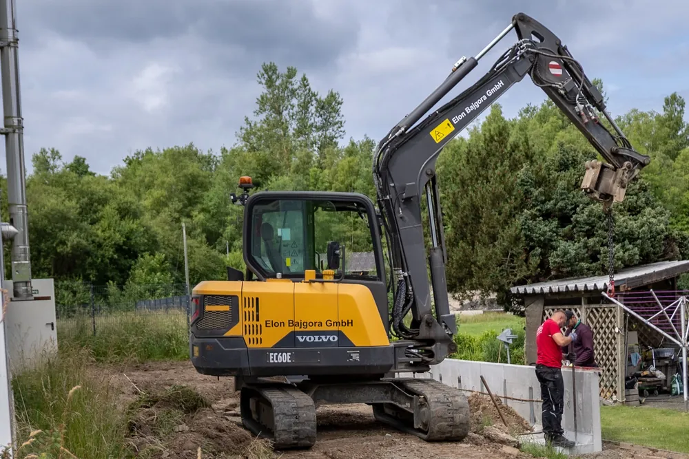 Bagger der Elon Bajgora GmbH setzt einen L-Stein in einem Privatgarten