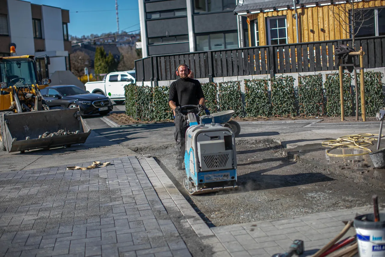 Fertige Pflasterfläche vor einem Neubau wird verdichtet
