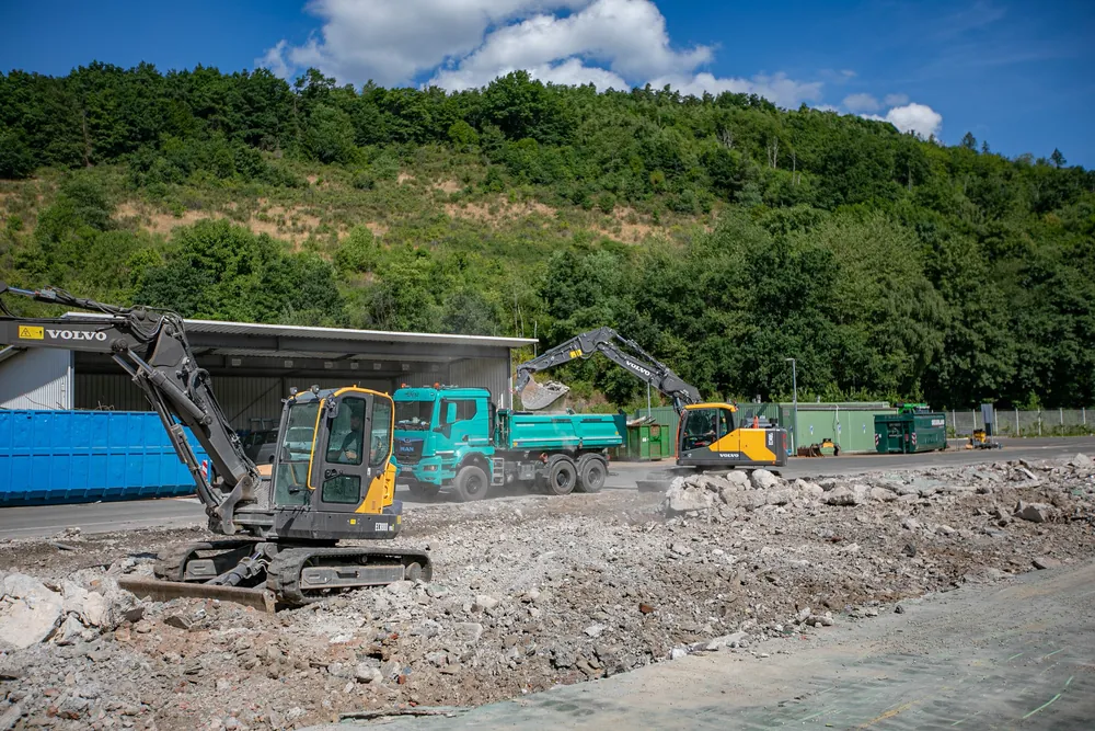 Zwei Bagger und ein Kipper im Einsatz auf einer Abbruchfläche im Tal