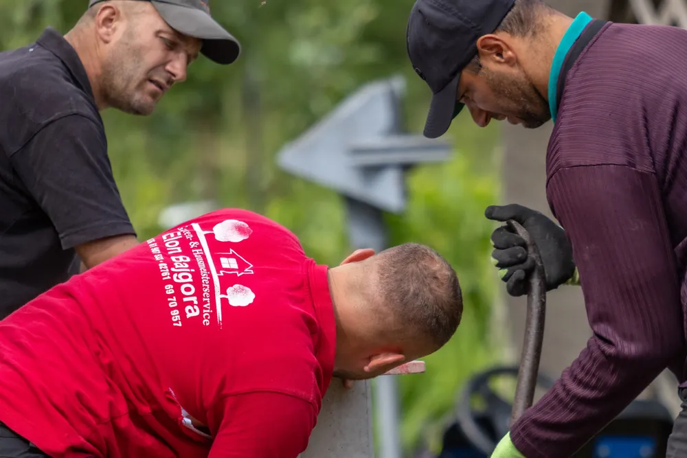 Drei Mitarbeiter richten einen L-Stein aus