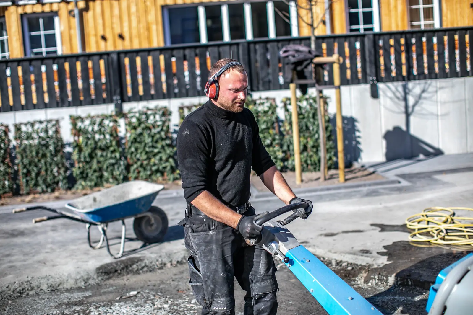 Mitarbeiter mit Gehörschutz verdichtet die neue Pflasterfläche mit der Rüttelplatte